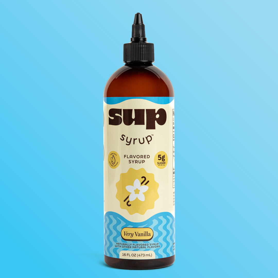 A 16 fl oz amber bottle of Sup Syrup Very Vanilla flavored syrup with a black twist open cap, set against a solid light blue background.