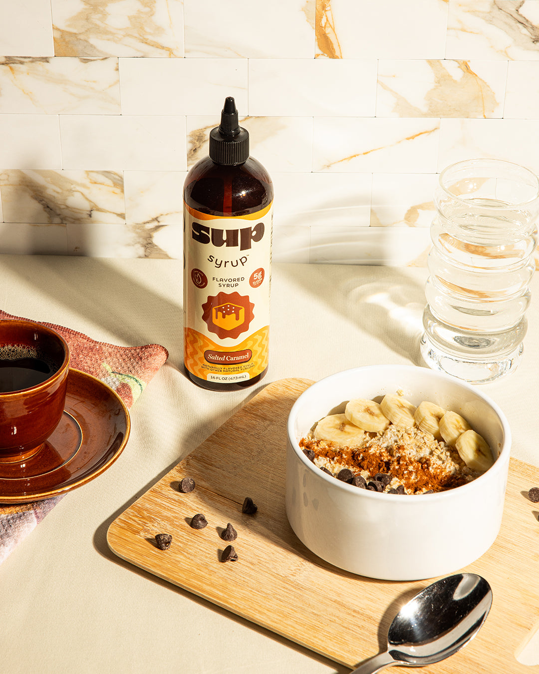 Sup Syrup bottle on a table with a bowl of oatmeal and a cup of coffee.